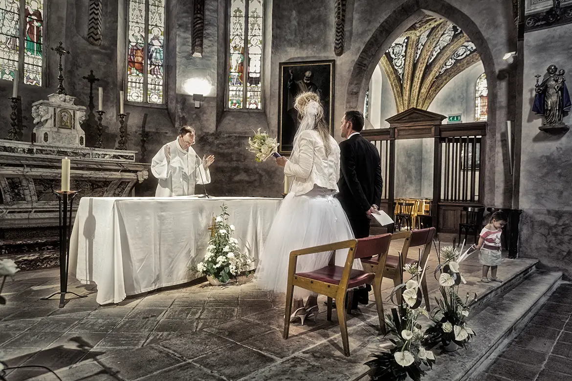 Mariés lors de la cérémonie à l’église capturés par un photographe de mariage dans une ambiance solennelle et lumineuse